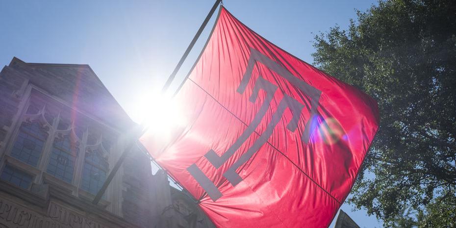 The cherry red Temple T lag waves against a bright sunny and blue sky